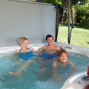 A family sitting under an open hot tub cover 